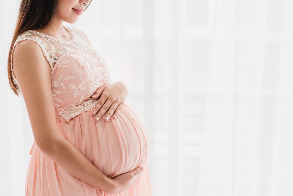 happy-beautiful-pregnant-woman-holding-pregnant-belly-near-window-home – small size